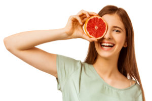 Teen girl holding grapefruit to eye