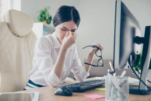 Woman rubbing eyes in front of a computer