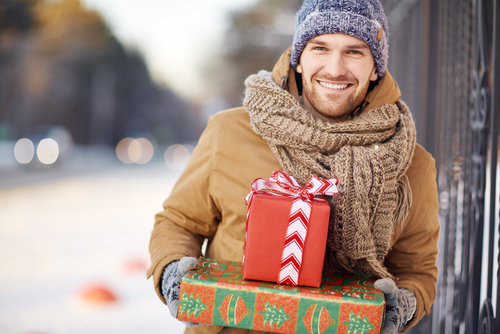 A man standing outside with presents in his hands 
